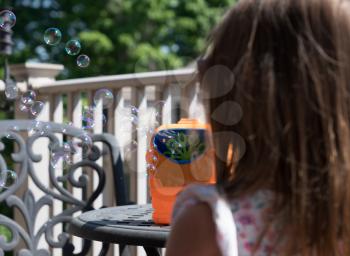 Childrens toy soap bubble blower with young girl watching the bubbles being blown