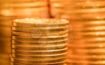 Focus on a stack of gold coins with other coin stacked in the background out of focus