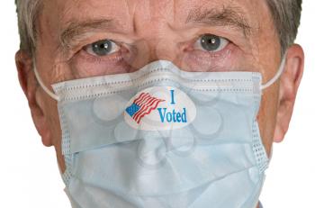 I Voted sticker on senior caucasian man's face mask as he stares for the presidential election in the USA. Isolated during coronavirus pandemic