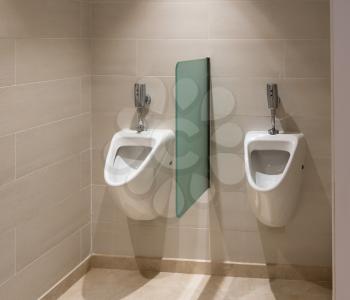 Pair of modern porcelain urinals with automatic flush in male bathroom