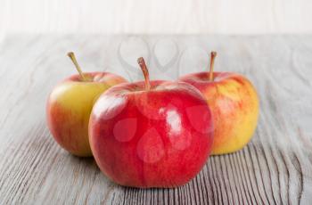 Ripe red apples on a wooden background. Three juicy apples on a table.