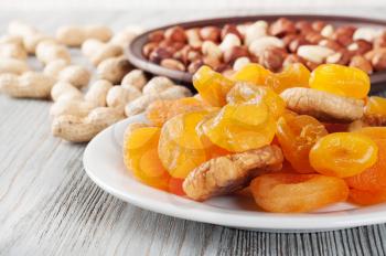 Dried fruits and nuts on a wooden background. Candied fruits, lemon, apricot, fig and nuts in plate. 