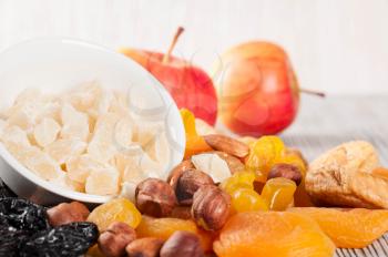 Dried fruits, red ripe apples and nuts on a wooden background