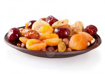 Dried fruits on a white background. Dates, lemon, apricots, figs and nuts in a clay plate. 