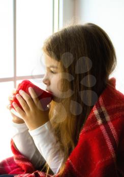 the little girl froze and wrapped herself in a blanket. Sits, looks out the window and drinks a hot drink