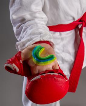 Children's hand in a red sports glove holds a protective cap for martial arts