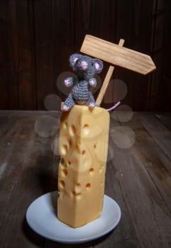 a small toy mouse the symbol of 2020 sits on a large piece of cheese with holes next to an empty plate with a place for inscription.