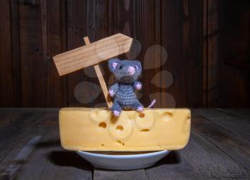 a small toy mouse the symbol of 2020 sits on a large piece of cheese with holes next to an empty plate with a place for inscription.