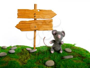 small toy mouse the symbol of 2020 sits under a wooden direction indicator in both directions on green artificial grass