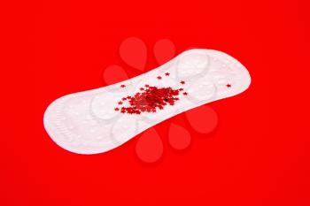 White feminine sanitary pad with impromptu monthly discharge on a bright red background