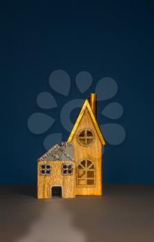 two cute wooden toy houses with windows and triangular roofs on a blue background
