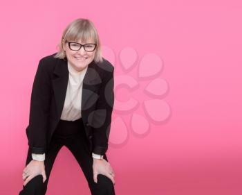 business woman in formal suit and glasses having fun on a pink background