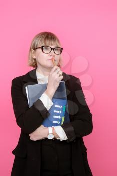 business woman in a formal suit and glasses is thinking on a pink background