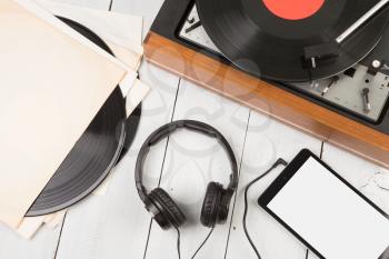Vintage turntable, smartphone and headphones on the wooden background