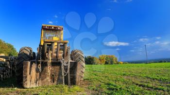 Old yellow digger parked on the field.