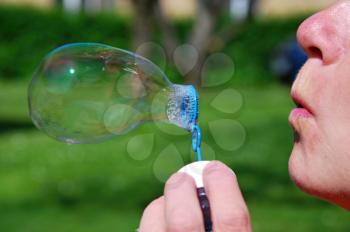 Woman blow into the soap bubble.