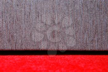 Detail of red carpet and grey sofa.