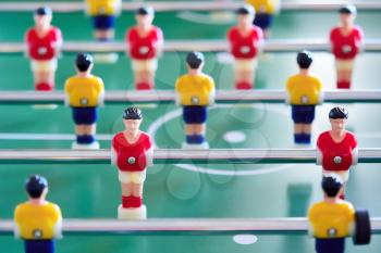 Closeup of the table football or foosball players in red and yellow jerseys.
