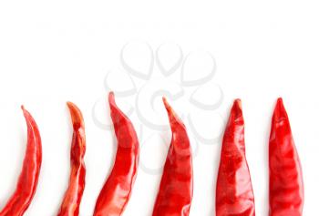 Top view of dried red hot chilli peppers halves arranged in a row. It looks like a chilli flames on white background with copy space on upper side.