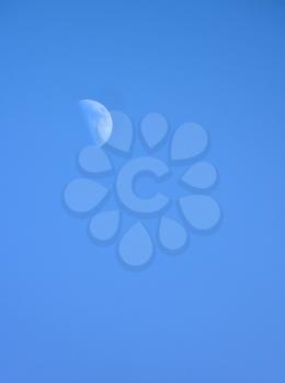 Half moon on blue sky background during daytime.