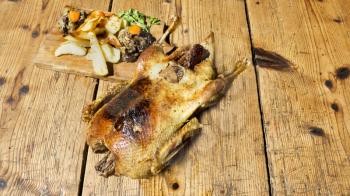 Roasted Duck With Potatos, Carots and Stuffing Resting On A Wooden Table