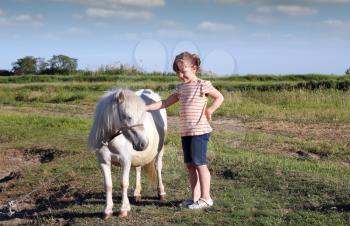little girl and white pony horse on pasture