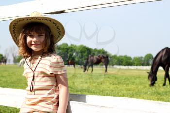 little girl with cowboy hat on farm
