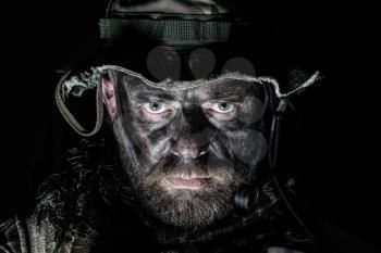 Special forces United States in Camouflage Uniforms studio shot. Wearing jungle hat, Shemagh scarf, painted face. Black background, bottom light
