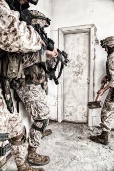 Marine assault team, counter-terrorism squad members, commando fighters in body armor, armed with service rifles, stalking through corridor to closed door, clearing rooms in abandoned city building