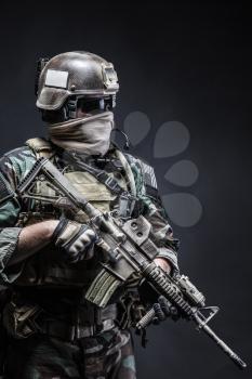 United states Marine Corps special operations command Marsoc raider with weapon. Studio shot of Marine Special Operator half-turning black background