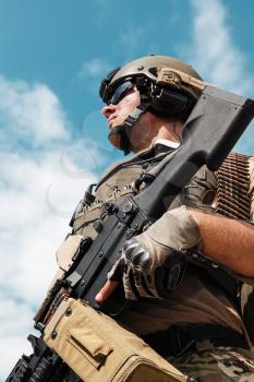 Low angle portrait of US Army Ranger with machinegun on blue sky background looking up. National pride concept