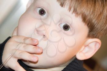 Little boy with wide and wondering eyes closes his mouth