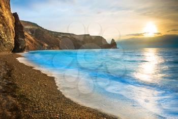 Sunset above tropical sea and rocks on the beach