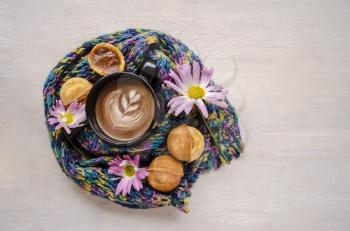 Still life with autumn chrysanthemums, baked nuts with condensed milk, cappuccino on the background of a knitted scarf. Autumn still life,