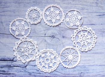 White hooked snowflakes on a gray wooden background. Inside the space for the text. Background for greetings and ads.