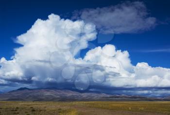 Beautiful cloud forms over the steppe prairie landscape with mountains in the background. Siberian Altai Mountains, Russia