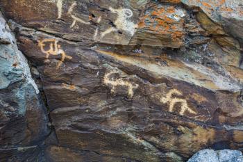 Hunting scenes prehistorical petroglyphs carved in rocks. Hunters on camels. Stones with petroglyphs in the Chuya Steppe, Kuray steppe in the Siberian Altai Mountains, Russia