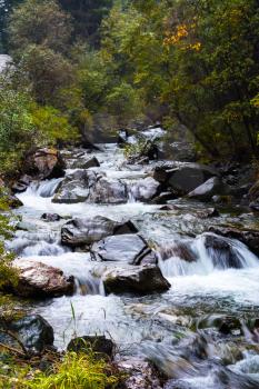 Mountain stream flowing over rocks. Cascade waterfalls. Altai Mountains, Russia