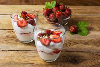 Layered dessert with cream, strawberry and ripe berries. Summer dessert with fresh strawberry.