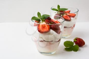 Layered strawberries dessert with cream cheese on white background. Whipped cream with fresh strawberry.