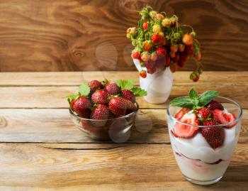 Ripe strawberry and summer layered cream cheese dessert. Whipped cream with fresh strawberry and wild strawberry in vase. Copy space.
