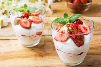 Strawberry with yogurt  on rustic wooden background. Layered cream dessert with ripe strawberry.