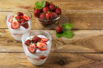 Summer layered cream dessert and ripe strawberry in glass bowl . Whipped cream with fresh strawberry. 