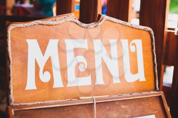 Menu wooden sign. Vintage brown board with white letters and surrounding rope in restaurant. List of foods offered. Selection. What to eat. Breakfast, lunch or dinner