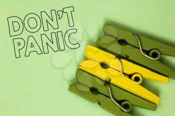 Text sign showing Don t not Panic. Conceptual photo sudden strong feeling of fear prevents reasonable thought Three green yellow vintage clothespins clear background Holding things
