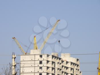 Crane and building construction site against blue sky.