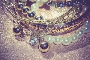 Stylish fashion bracelets with acrylic beads, pearls on vintage glittering background.