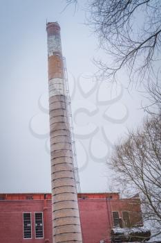 Old red brick factory building and smoke stack in rural.