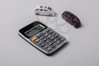 Little size cars beside a calculator on white background