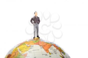 Man figurine standing at the top of a globe on a white background